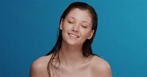 Pretty Woman With Wet Hair After Shower Looking To Camera With Smile On Blue Background Stock