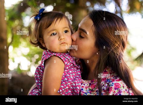 Young Woman Kissing Serious Looking Baby Girl Stock Photo Alamy
