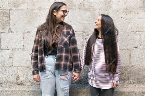 Premium Photo Two Young Lesbians Holding Each Other And Standing Near A Stone Wall Smiling Happy