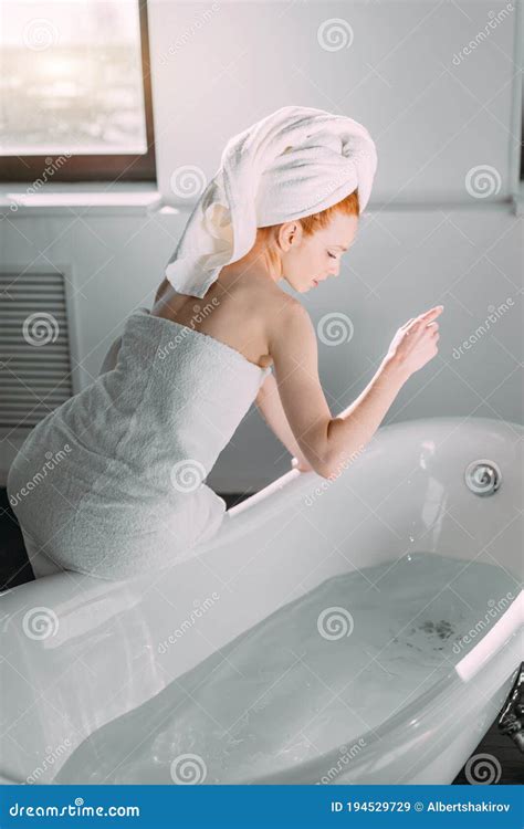 Smiling Woman Sitting On Bathtub Edge Running The Bath Testing Water