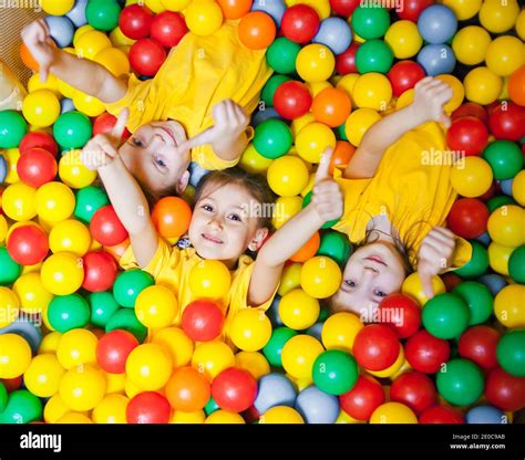 Three Happy Little Kids Girls In Ball Pit Smiling Happily At Camera And