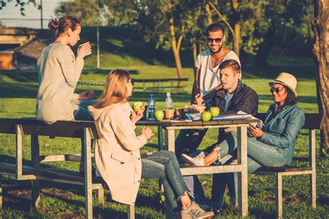 Multi Ethnic Group Of Friends Drinking Coffee And Chatting In A Park