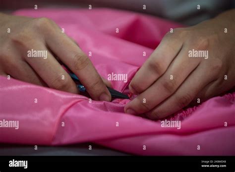 A seamstress cuts off excess thread of a newly sewn personal protective