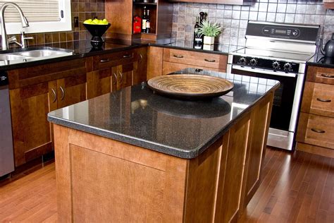 The kitchen island features black and white granite countertops with a dark wood casework base, similar to that of the curved breakfast bar with studded white leather upholstery. Dark Green Granite Countertops - Madison Art Center Design