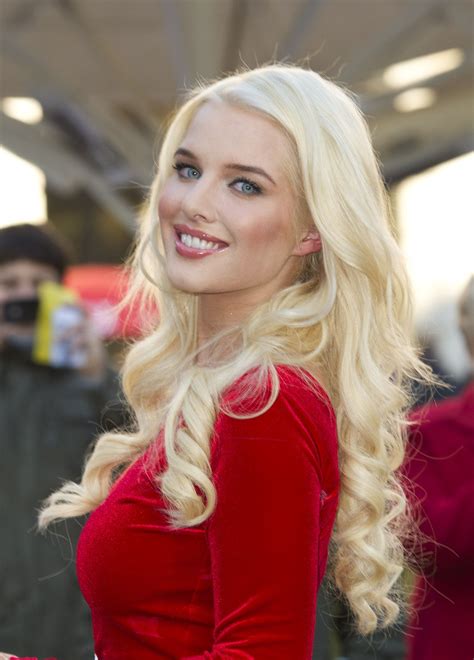 A Woman With Long Blonde Hair Wearing A Red Dress And Smiling At The Camera While Standing In