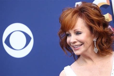 A Woman With Red Hair Smiling At The Camera And Wearing Earrings On Her