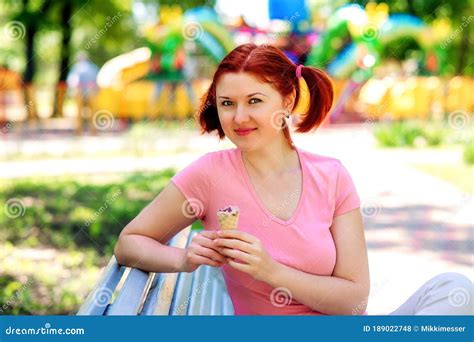 Smiling Young Woman With Pigtails Hairstyle And Pink Shirt Sitting On