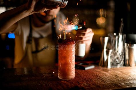 Bartender Sprinkling To The Red Cocktail In The Glass With A Crushed Ice A Spices And Burning