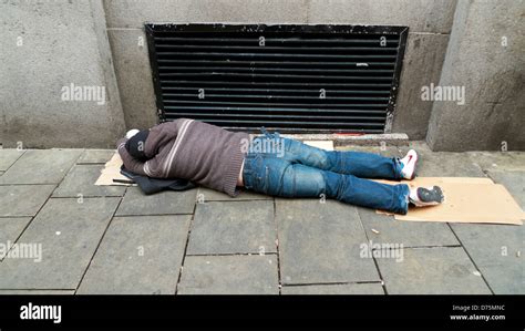 Man Prostrate Asleep Maybe Drunk Or Hungover Passed Out On Pavement By Heating Vent To Keep