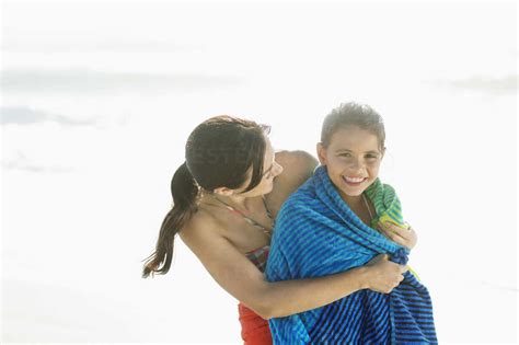 Mother Wrapping Daughter In Towel On Beach Lizenzfreies Stockfoto
