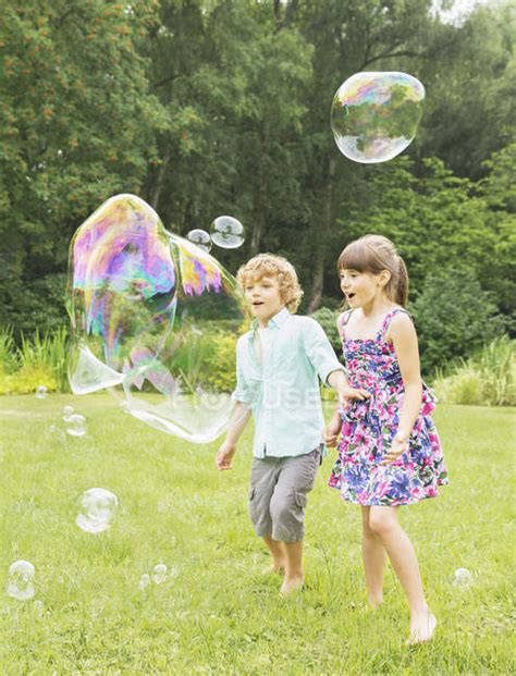 Children Playing With Bubbles In Backyard — Togetherness Playful