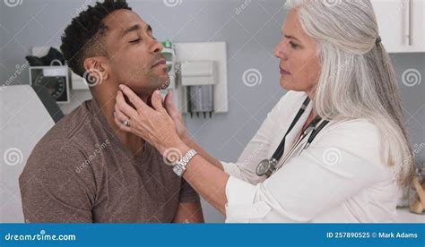 Close Up Of Senior Female Doctor Examining Male Patients Neck Stock