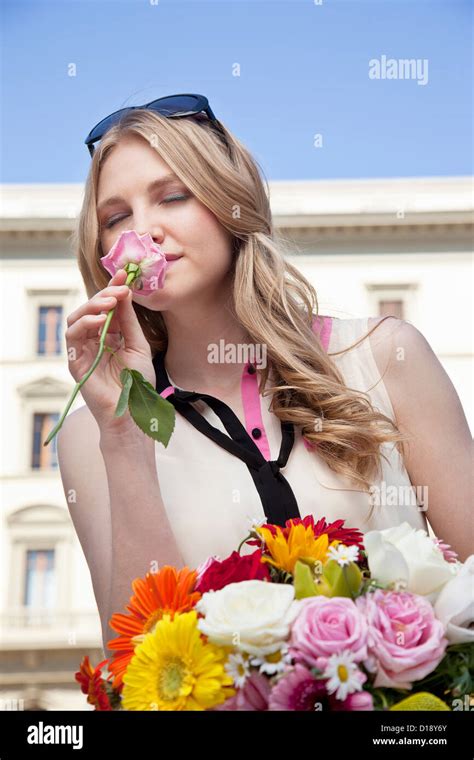 Young Woman Smelling Rose From Bouquet Of Flowers Eyes Closed Stock