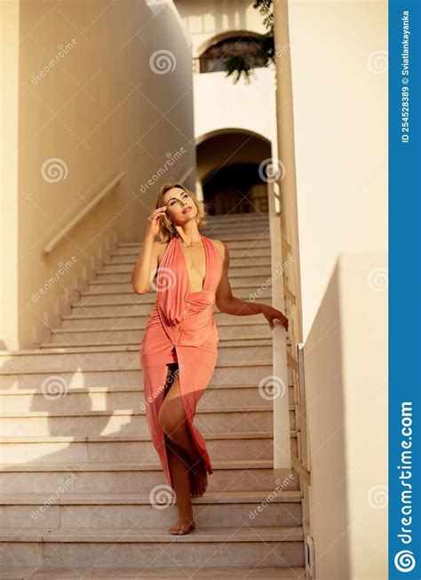 A Beautiful Girl Posing On The Stairs In A Light Long Dress A Resort