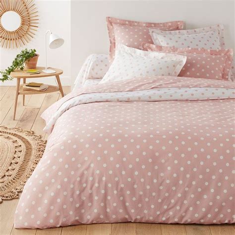 A Bed Covered In Pink And White Polka Dot Comforter With Pillows On The