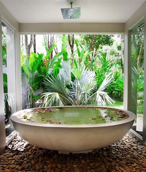 a large bath tub sitting in the middle of a bathroom next to a lush green forest