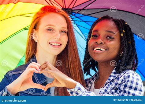 Latin Hispanic And Redhaired Ginger Women Holding Rainbow Umbrella In