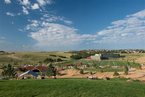 An Aerial View Of A Green Field With Buildings In The Distance