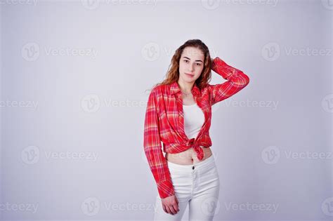 Young Girl In Red Checked Shirt And White Pants Against White
