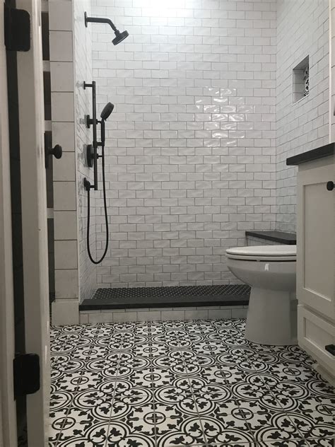 A Bathroom With Black And White Tiles On The Floor Shower Head Toilet