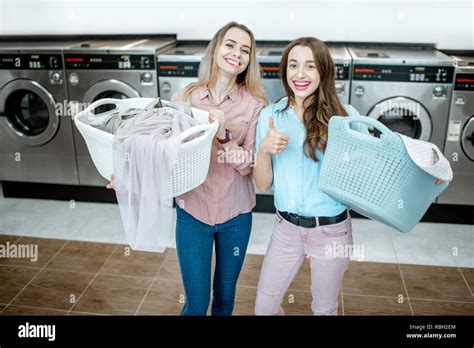 Portrait Of A Two Cheerful Girlfriends Standing Together With Baskets Full Of Clothes For