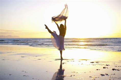 Young Woman Dancing On Sunlit Beach Stock Photo