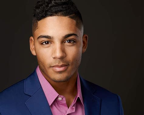 A Man In A Blue Suit And Pink Shirt Is Looking At The Camera With A Serious Look On His Face