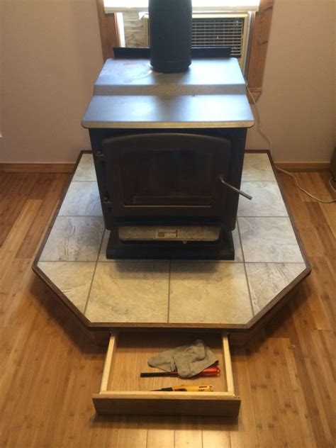 I love the look of wood mantels but am nervous having wood so close to the stove pipe. Tile wood stove base with drawer | Wood tile, Wood, Wood stove