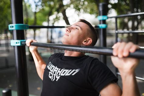 Young Man Doing Pull Ups On Horizontal Bar Outdoors Workout Sport