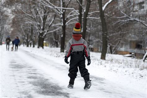 Boy Walks In The Winter Park Child Walks Along Snowy Road Back View