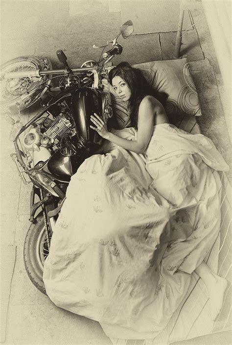 A Woman Laying In Bed Next To A Motorcycle