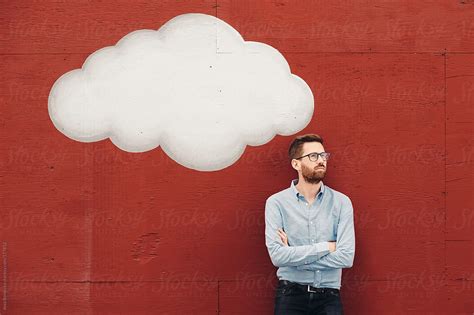Man Dreaming Big Ideas In His Cloud On A Red Wall By Stocksy