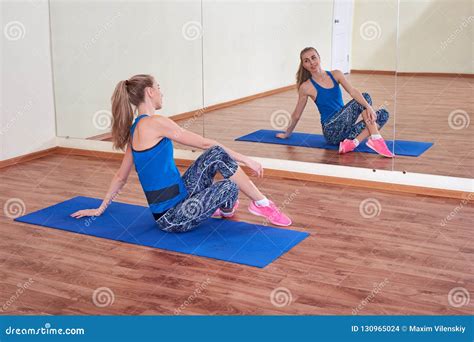 fitness woman stretching her body before workout in front of the mirror at the gym stock