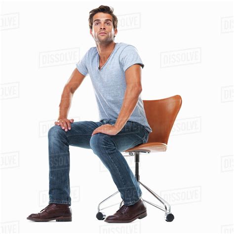 Studio Shot Of Young Man Sitting On Chair With Hands On Laps Stock