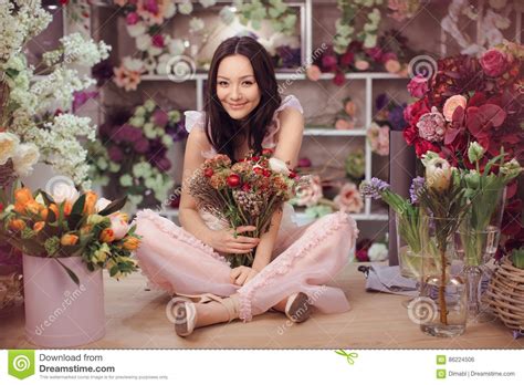 Beautiful Asian Woman Florist In Pink Dress With Bouquet Of Flowers In Hands In Flower Store