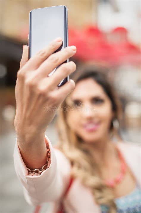 Smiling Young Woman Taking Selfies With Smartphone On City Street Stock