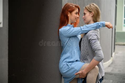 Liebende Lesbische Mädchen Die Stellung Auf Hintergrund Der Blauen Mauer Umarmen