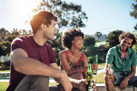 Multiracial Group Of Friends Sitting Outside House And Having Beers