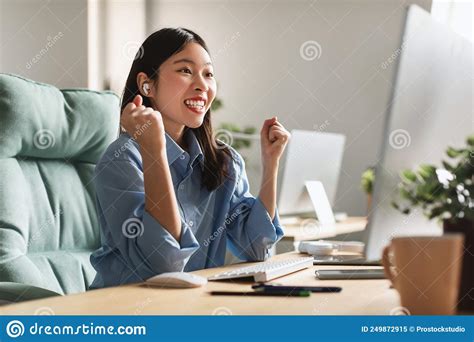 Japanese Businesswoman Shaking Fists Looking At Computer In Modern