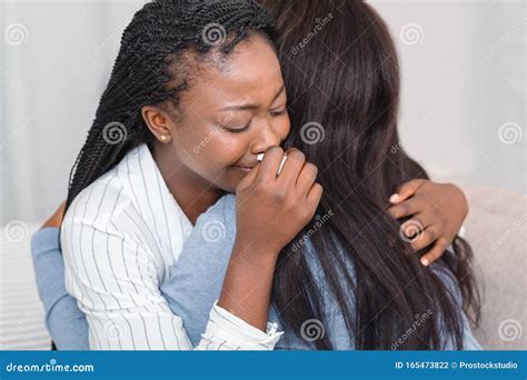 Girl Hugging And Consoling Her Crying Friend At Home Stock Photo