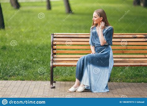 Beautiful Girl Sitting On A Bench Brunette In A Bright Dress Sunny