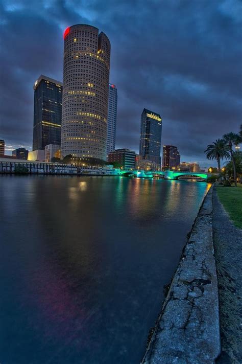 The City Is Lit Up At Night Along The Waters Edge With Lights