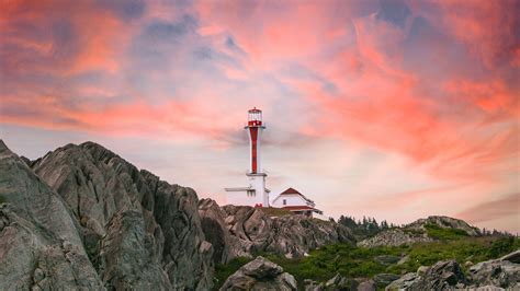 Lighthouse On Rocks In Light Orange Blue Sky Background Hd Nature