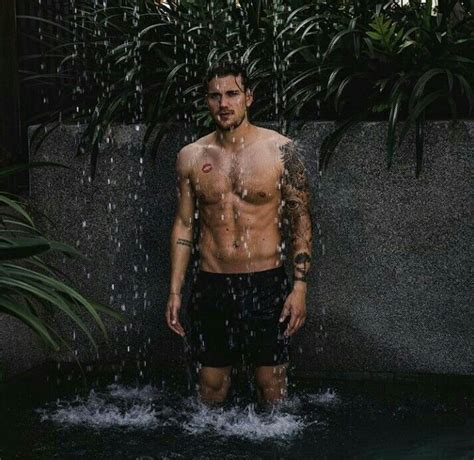 A Man Standing In The Water With His Shirt Off And No Shirt On Under A Rain Shower