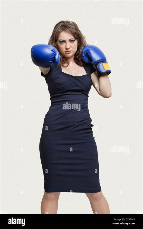 Portrait Of A Young Woman Wearing Blue Boxing Gloves Against Gray