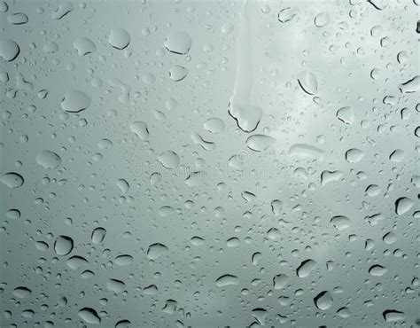 Water Droplets From Rain Splash On Clear Glass With Gray Background Of