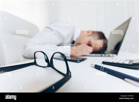 Tired Businessman From Heavy Workload Sitting At The Desk Stock Photo