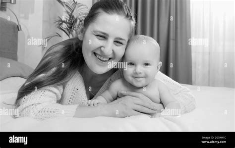Black And White Portrait Of Happy Smiling Baby And Mom Lying On Bed