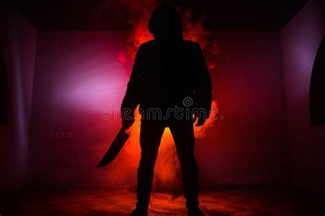 A Dangerous Hooded Man Standing In The Dark And Holding A Knife Face Can Not Be Seen