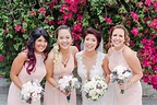 Bride and her bridesmaids in front of a colorful tree laughing ...